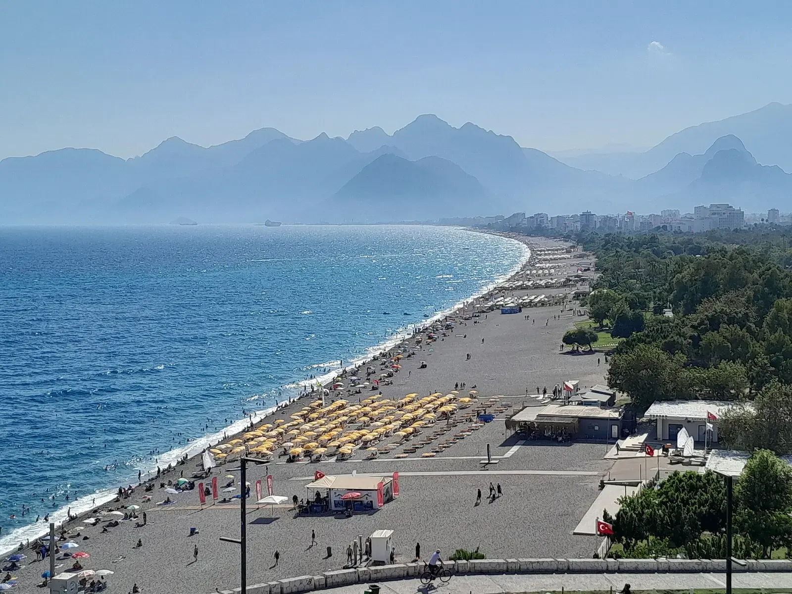 Het drukke kiezelstrand van Konyaaltı met de bergen in de verte